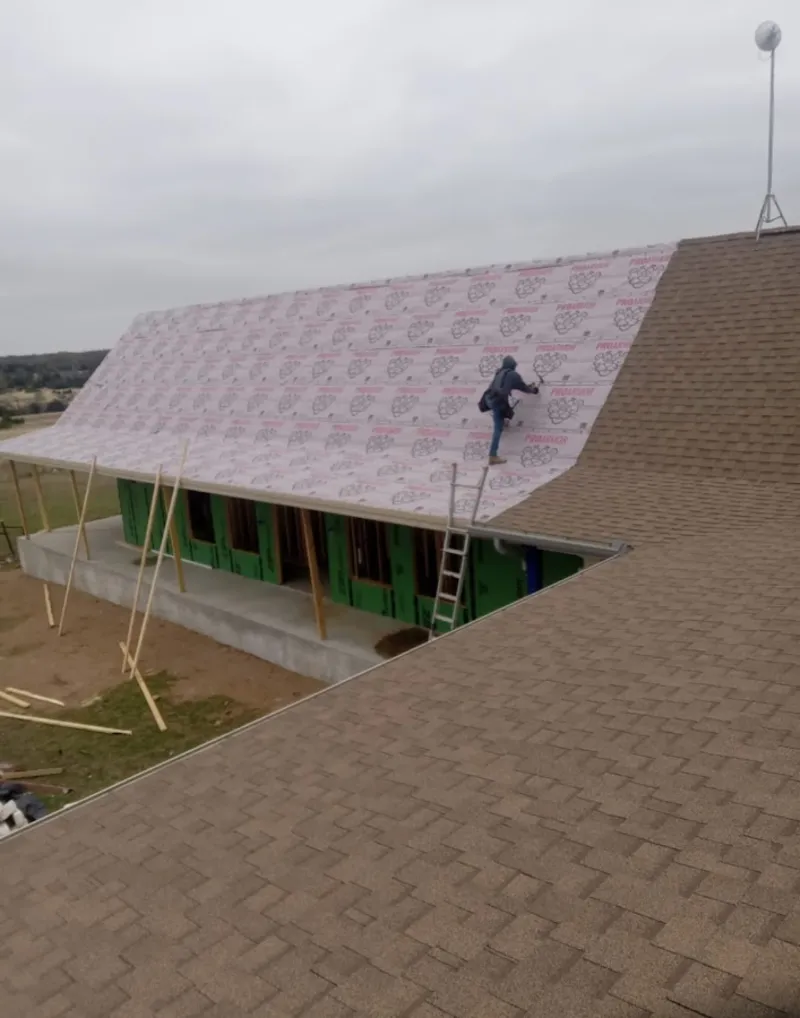 Worker preparing underlayment for a metal roof installation in Riverdale